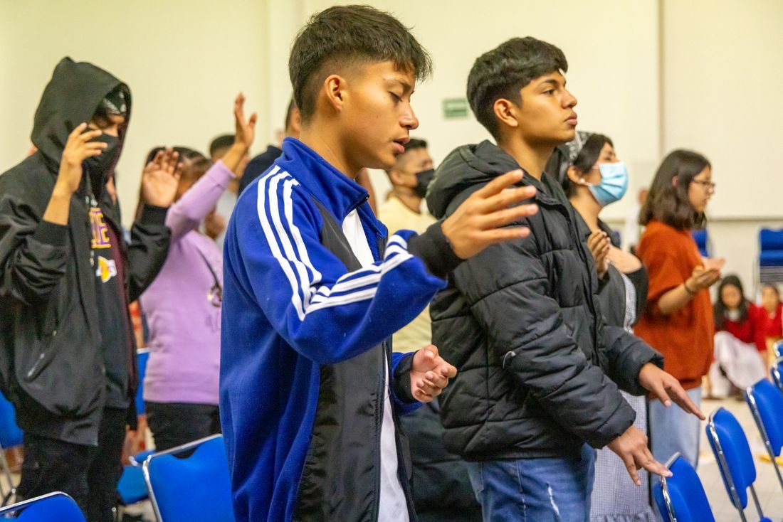 Teenagers worshipping with hands on their hearts
