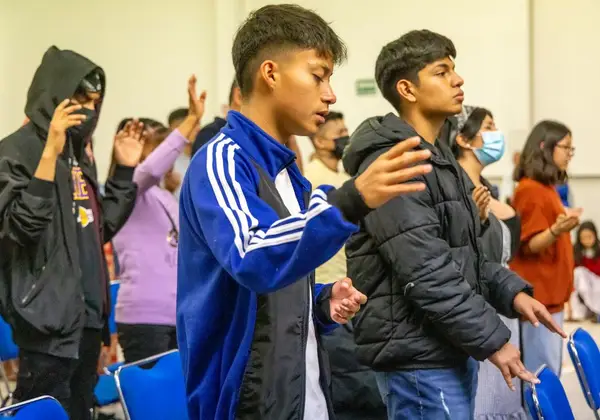 Teenagers worshipping with hands on their hearts