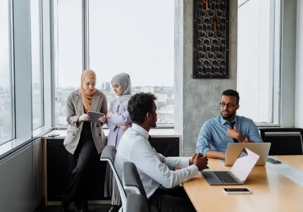 A diverse team in conversation by bright office windows