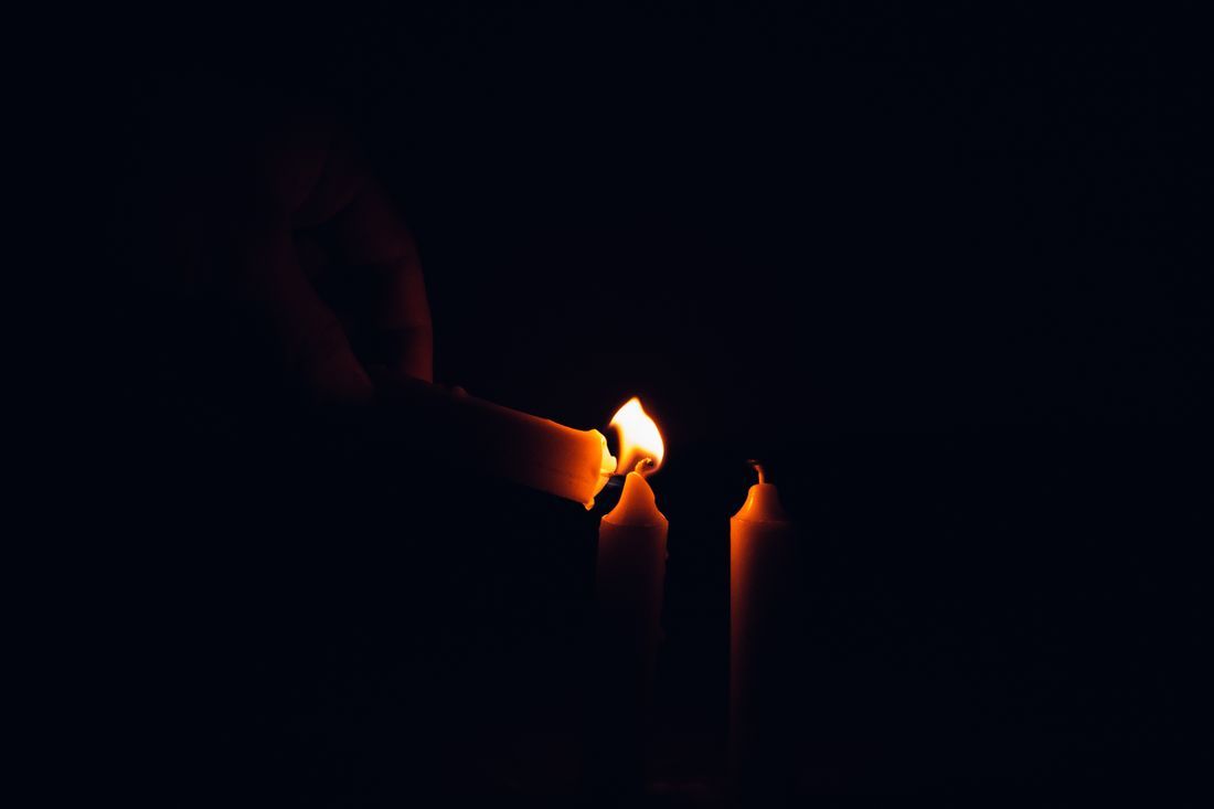 A hand lighting candles in a quiet vigil