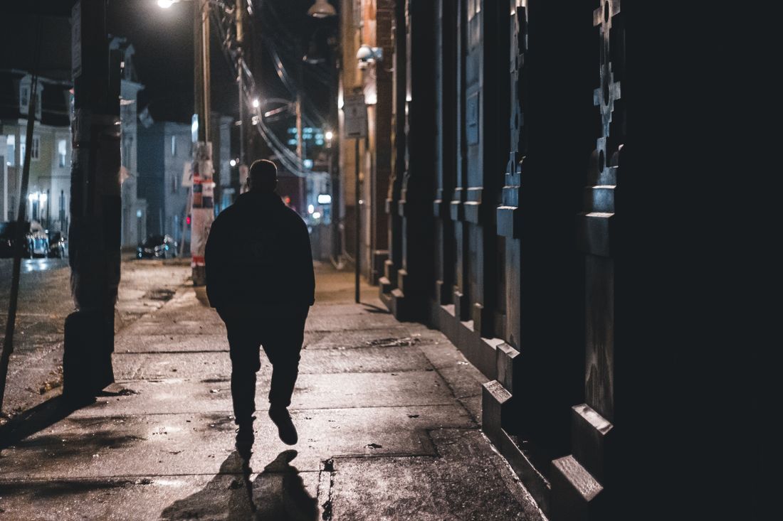 A man walking alone down a city street at night