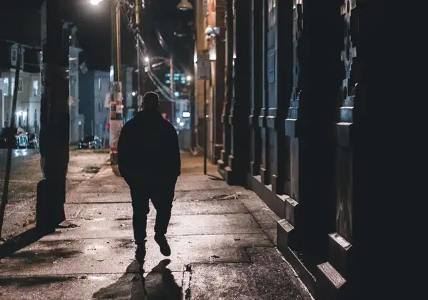 A man walking alone down a city street at night