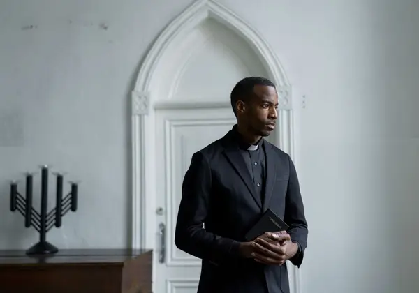 A pastor holding a Bible, deep in thought