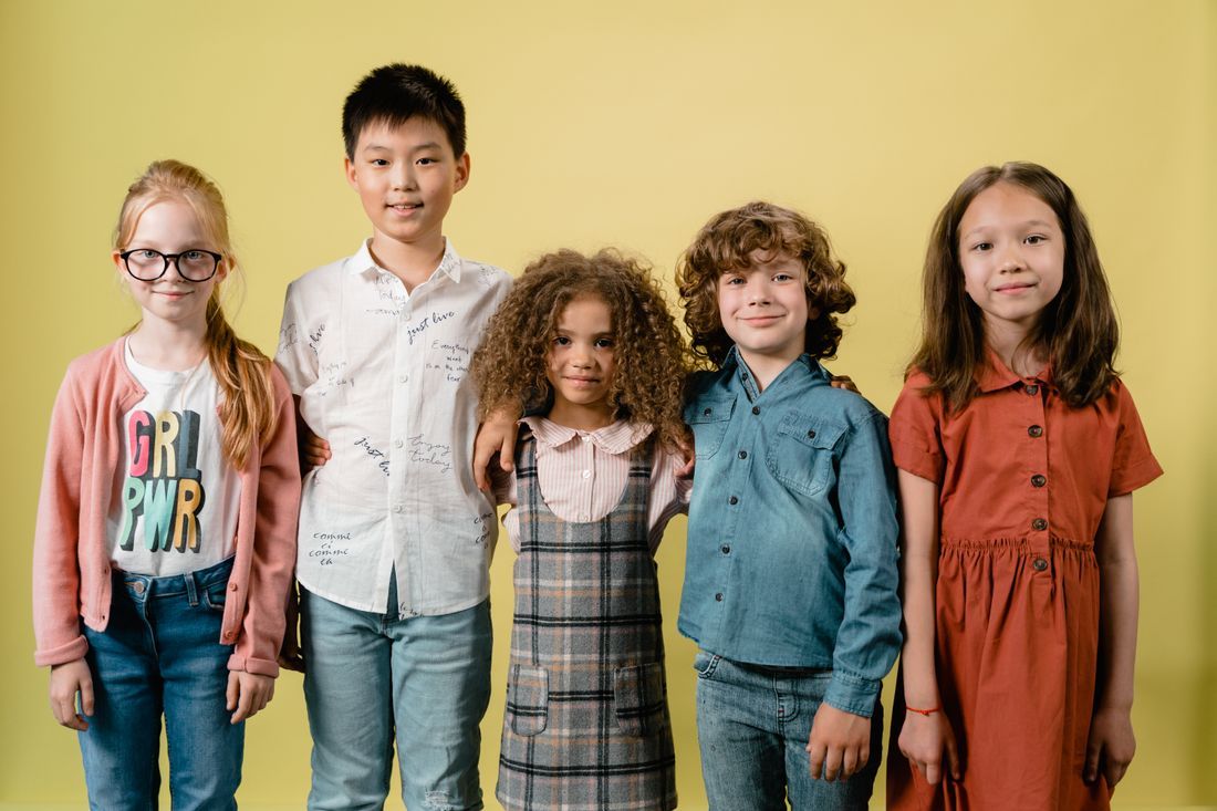 Five diverse children standing arm in arm, smiling