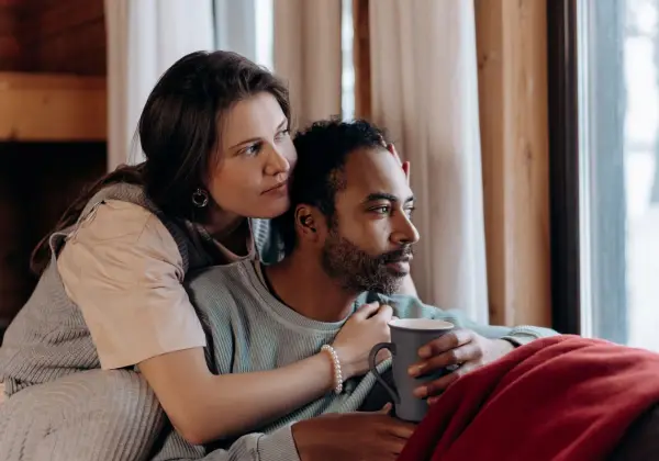 A couple sitting close together by a window with coffee