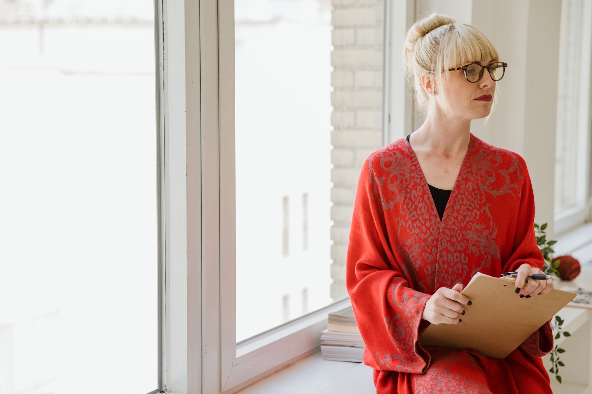 A woman leader with a clipboard pausing by a bright window