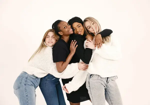 Women of different backgrounds holding one another close