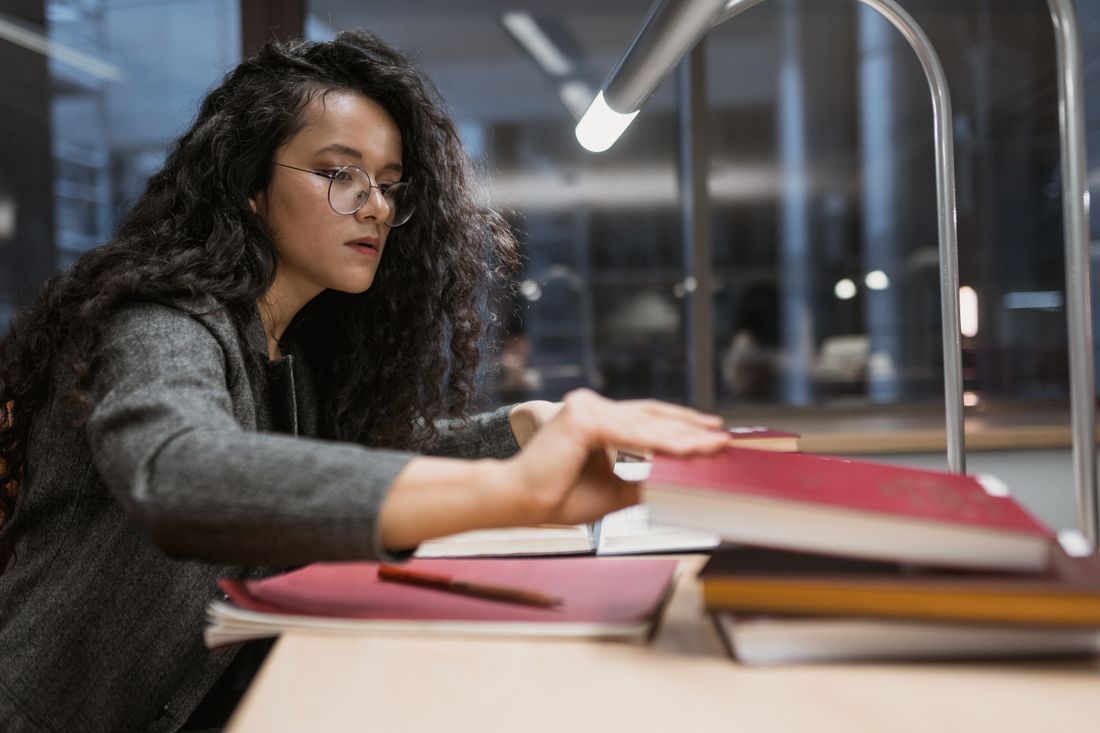 A college student studying late at night under a library lamp