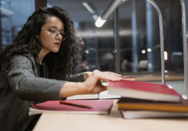A college student studying late at night under a library lamp