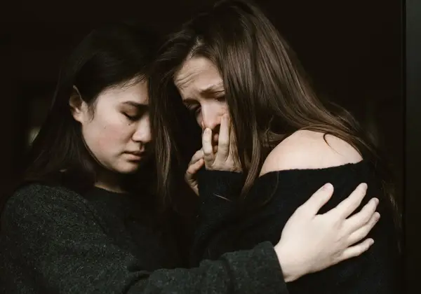 Two women embracing tenderly in shared grief
