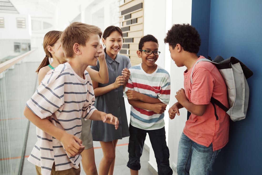 Diverse middle schoolers laughing together in a school hallway