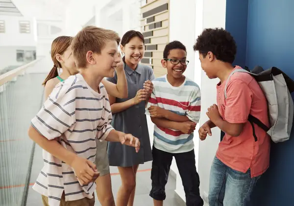Diverse middle schoolers laughing together in a school hallway