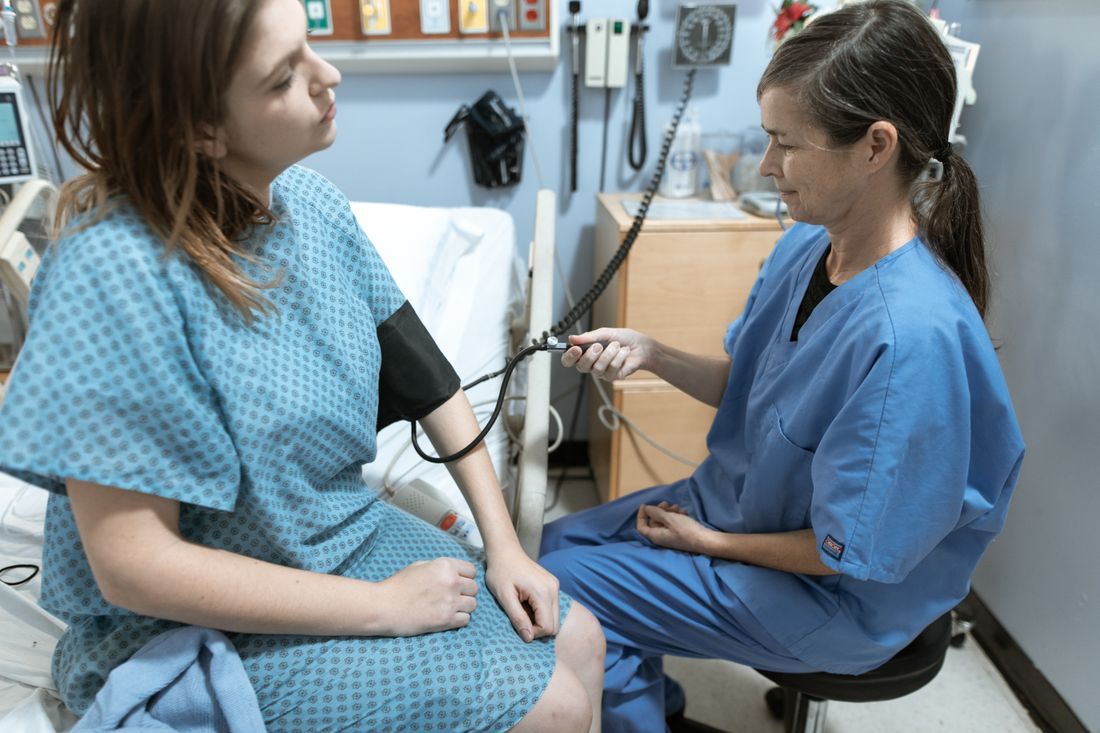 An experienced nurse checking a young patient's blood pressure