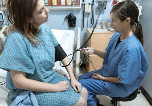 An experienced nurse checking a young patient's blood pressure