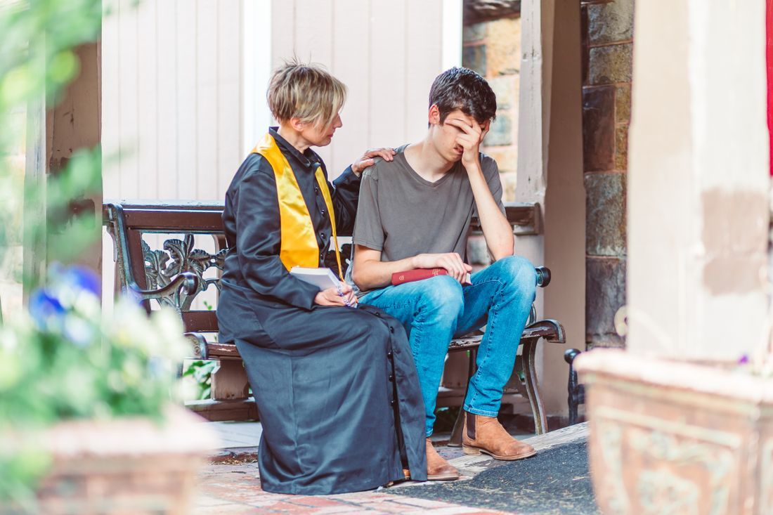 A pastor comforting a distressed young man on a bench