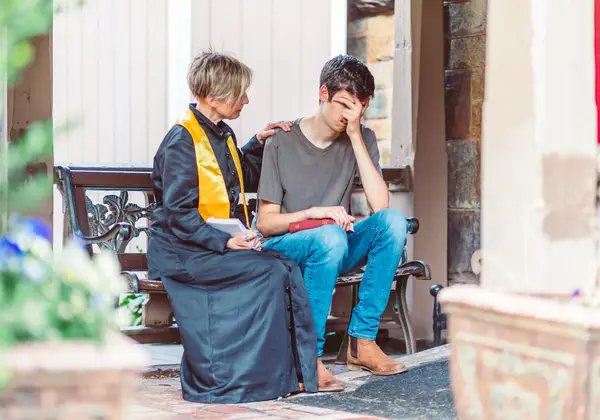 A pastor comforting a distressed young man on a bench