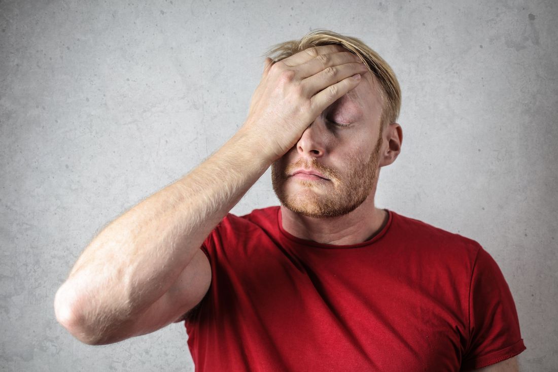 A weary man with a hand over his face
