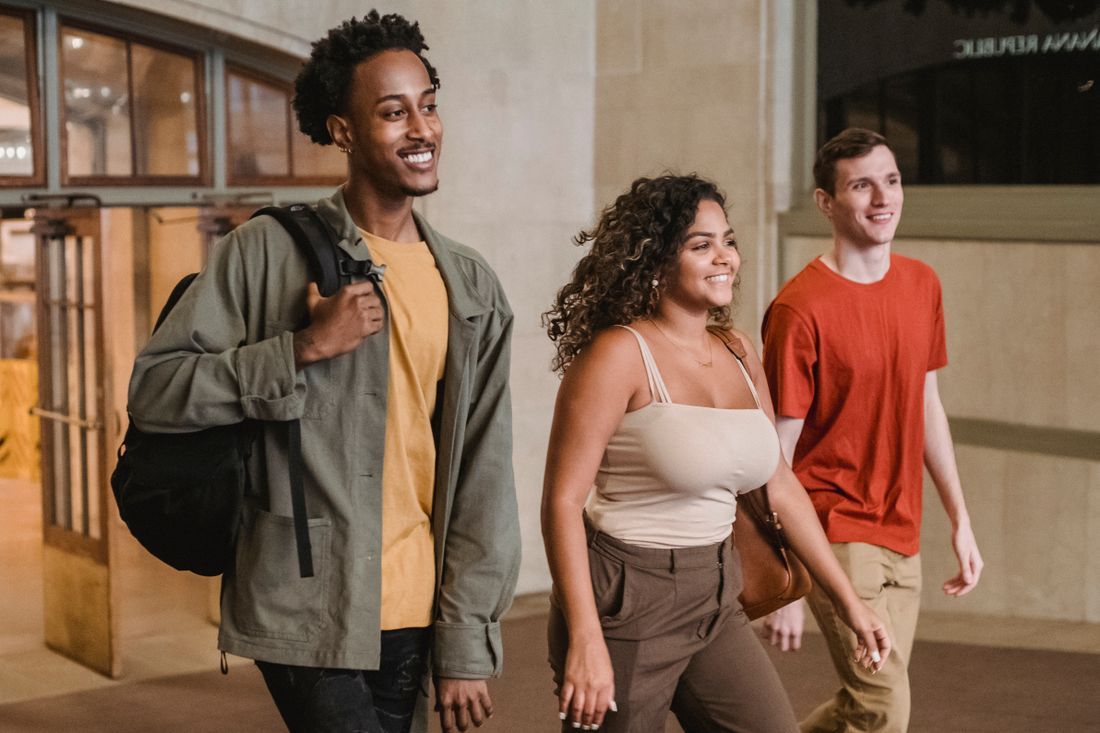 Three diverse college friends walking and laughing together
