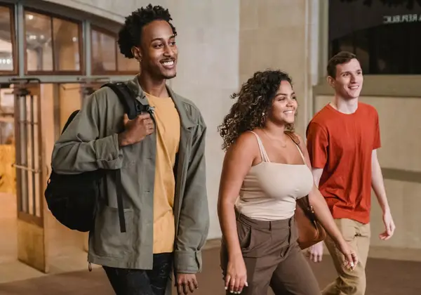 Three diverse college friends walking and laughing together