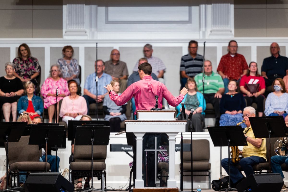 A conductor leading a choir and orchestra in worship