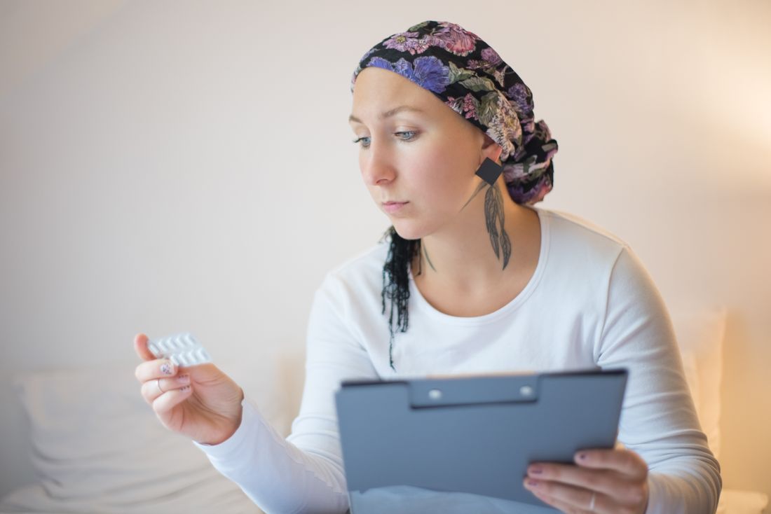 A patient in a headscarf reviewing her treatment with steady resolve