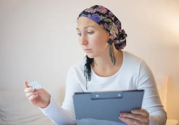 A patient in a headscarf reviewing her treatment with steady resolve