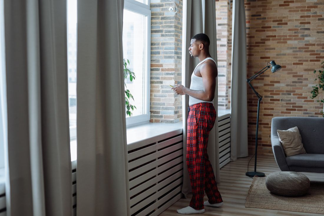 A man standing at the window in the early morning, thinking