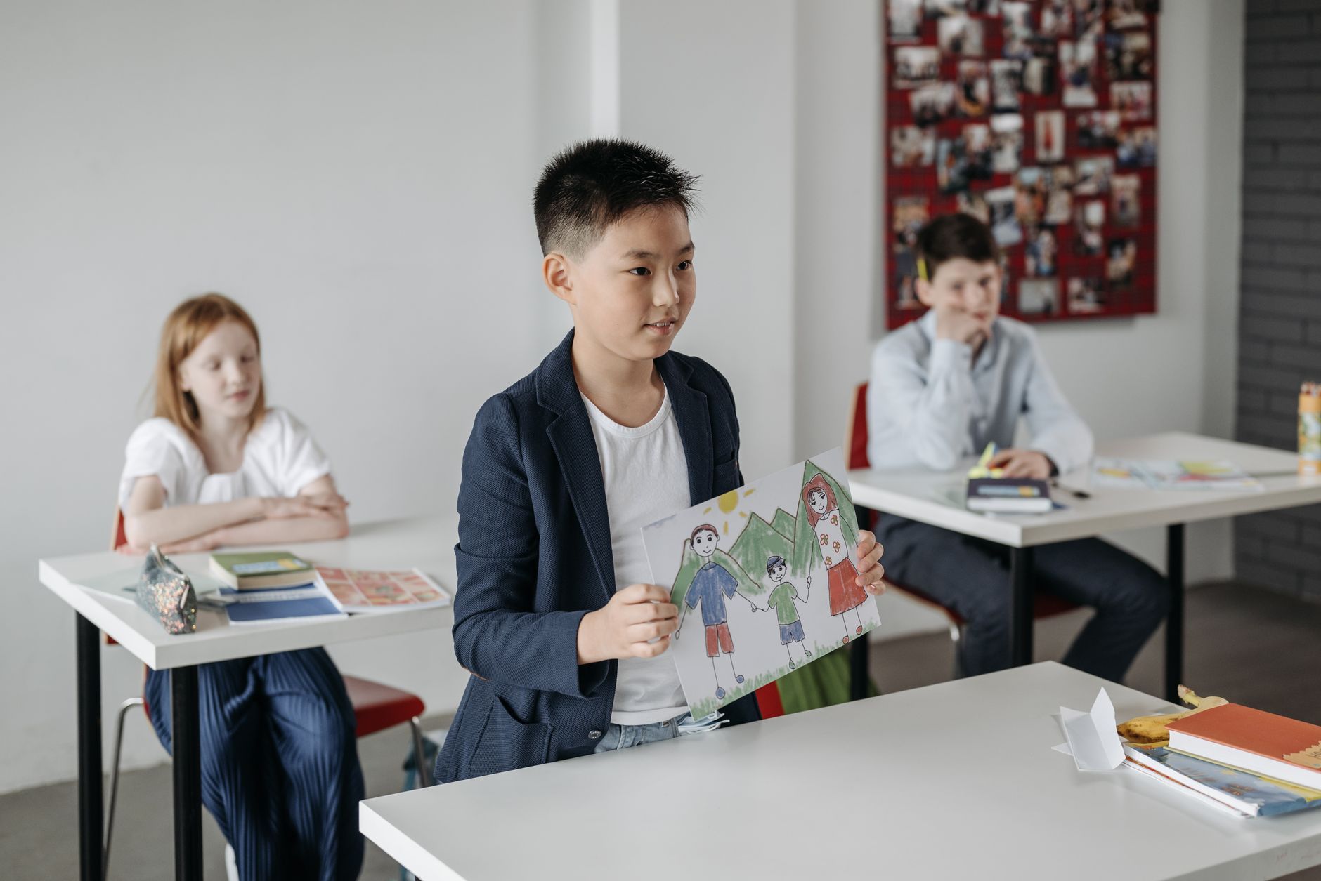 A Japanese boy showing a drawing of his family at school