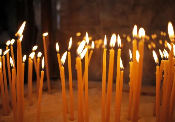 Tall prayer candles glowing warmly in a church