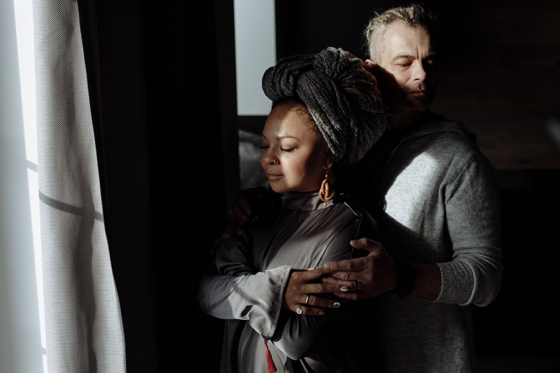 A couple embracing quietly by a window
