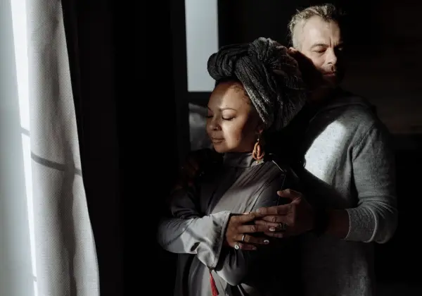 A couple embracing quietly by a window