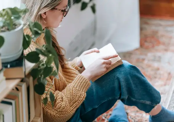 A woman reading quietly by a sunlit window