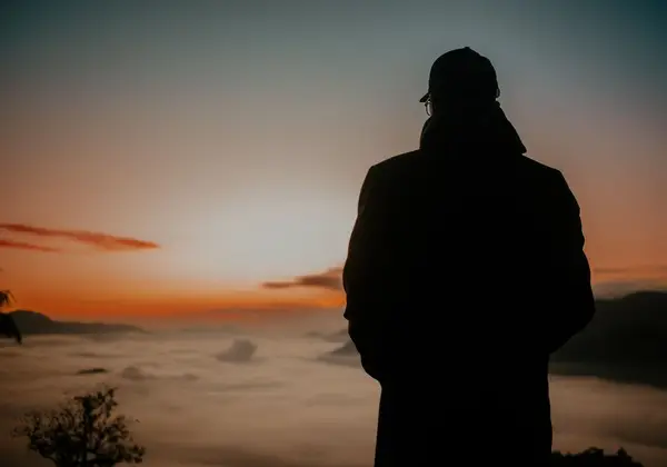 A person looking out over the clouds toward a new dawn