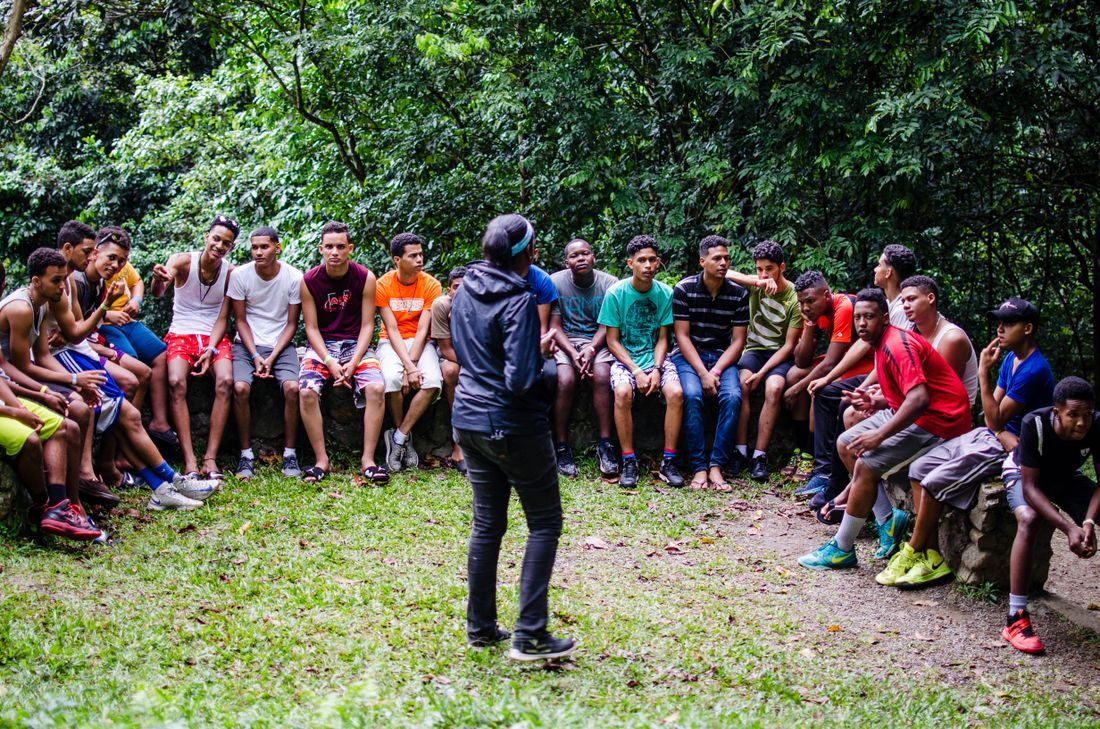 A leader teaching a circle of teenage boys outdoors