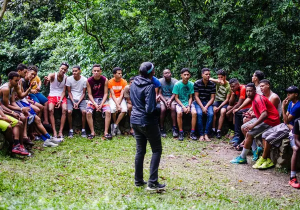 A leader teaching a circle of teenage boys outdoors