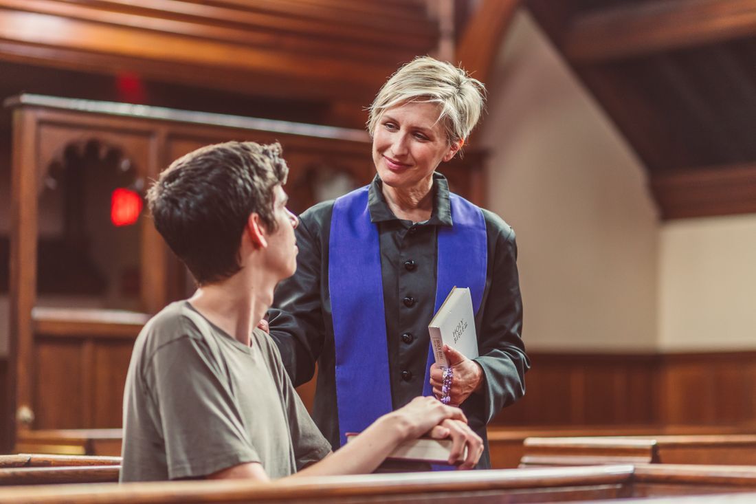 A youth leader warmly encouraging a teenager in a church