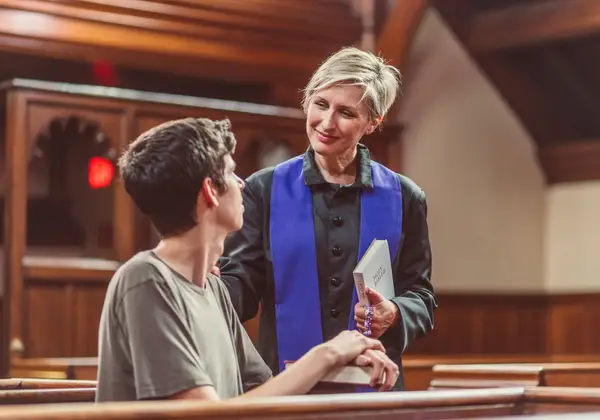 A youth leader warmly encouraging a teenager in a church