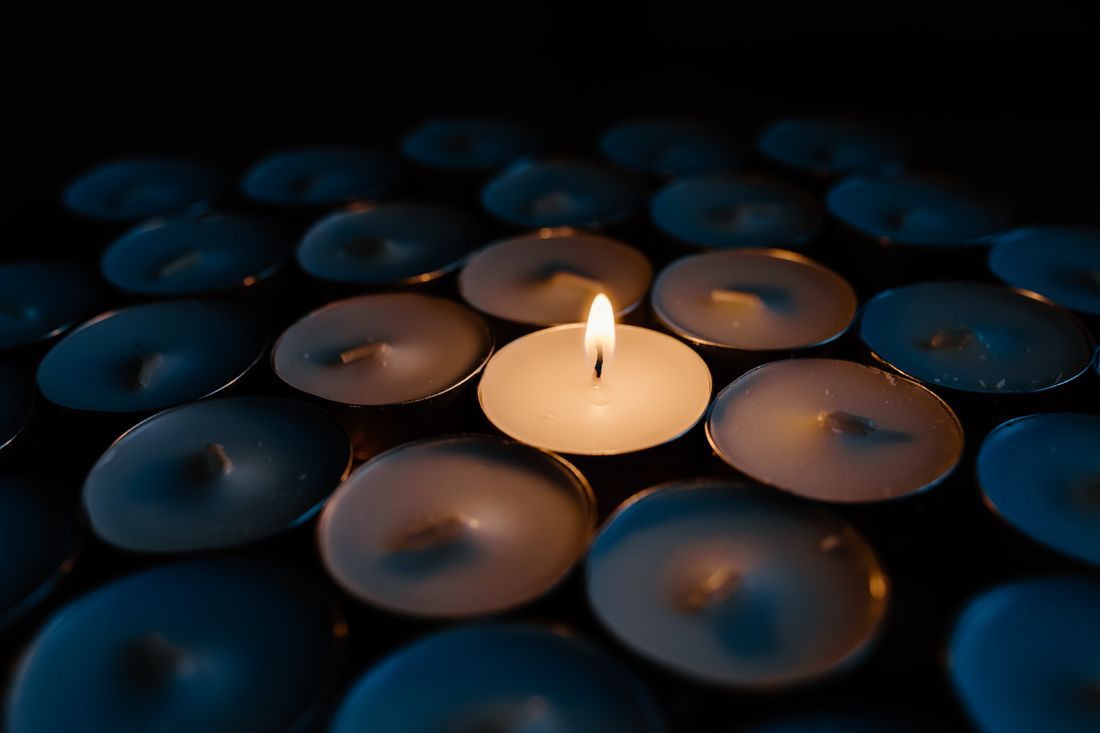 A single candle glowing among many, in remembrance