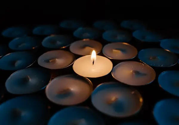 A single candle glowing among many, in remembrance