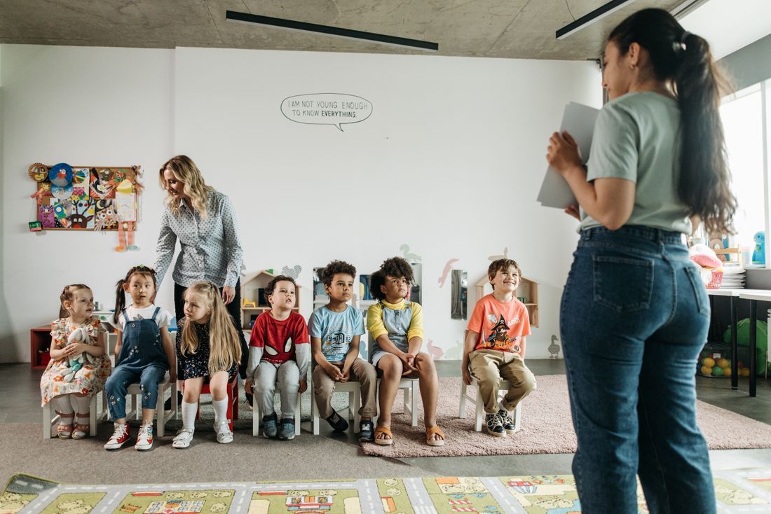 A teacher with a row of diverse preschoolers in a church classroom
