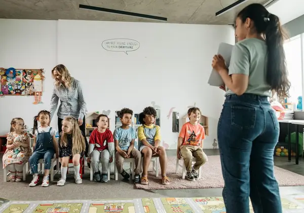 A teacher with a row of diverse preschoolers in a church classroom