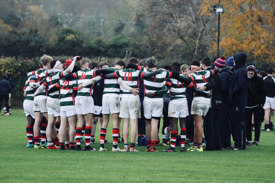 A team gathered arm-in-arm in a huddle
