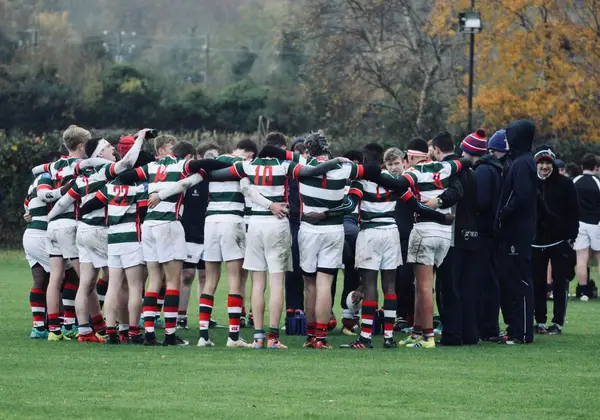 A team gathered arm-in-arm in a huddle