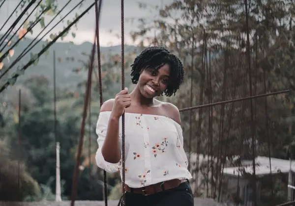 A woman smiling brightly outdoors in a floral top