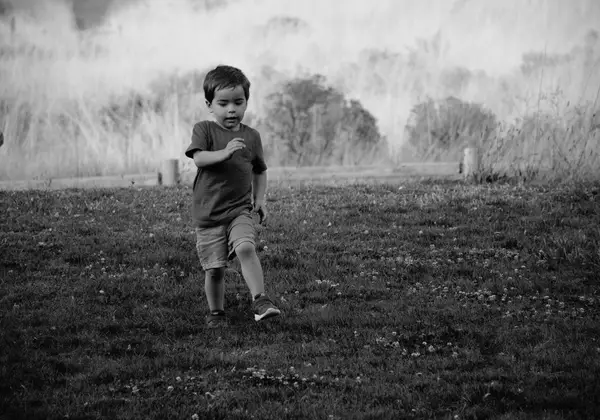 A little boy running freely through an open field