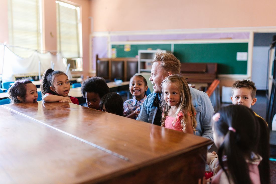 A children's leader laughing with a group of kids gathered around