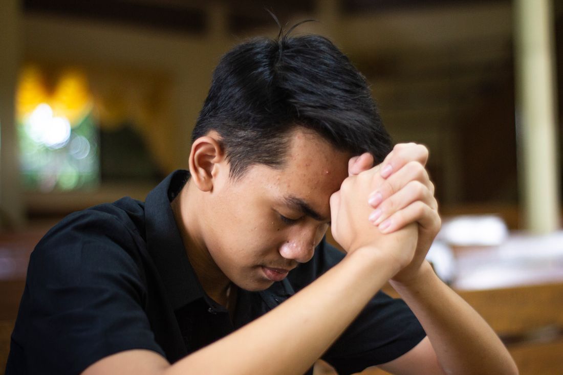 A man sitting alone, head bowed, reaching out for help