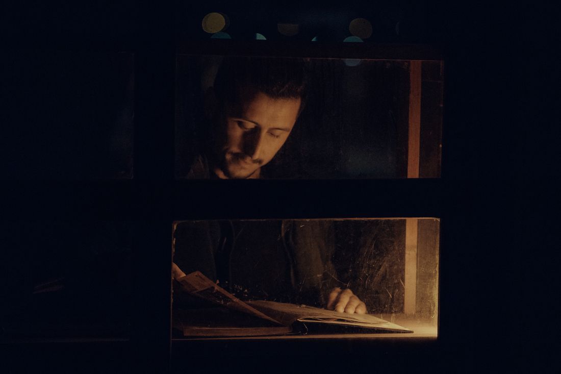 A man reading a book by warm light in the dark