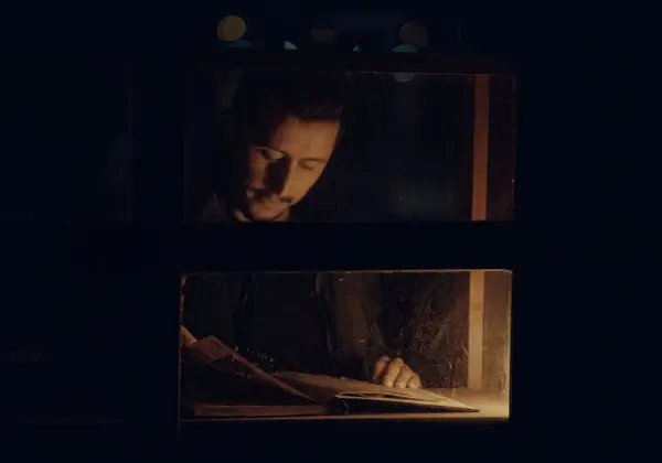 A man reading a book by warm light in the dark