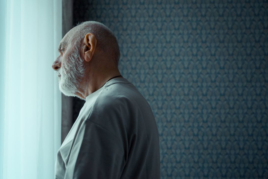 An older man at the window, reflecting quietly